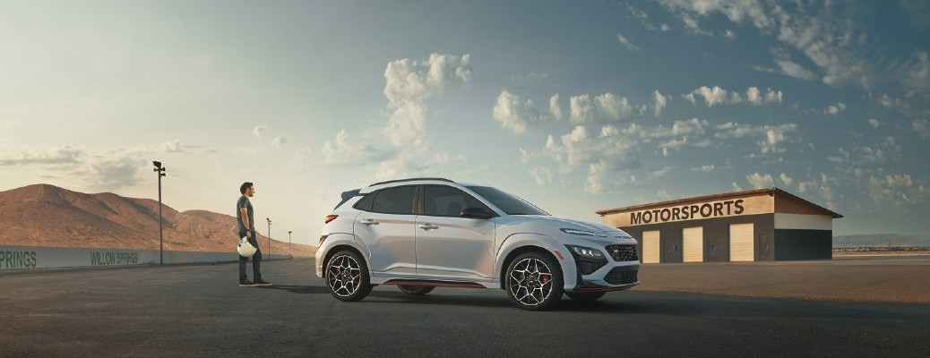 A man holding a helmet standing next to a 2022 Hyundai Kona N