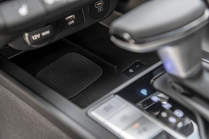 A Hyundai service technician in a navy and grey uniform uses a pneumatic impact wrench to work on a vehicle tire in a professional garage.