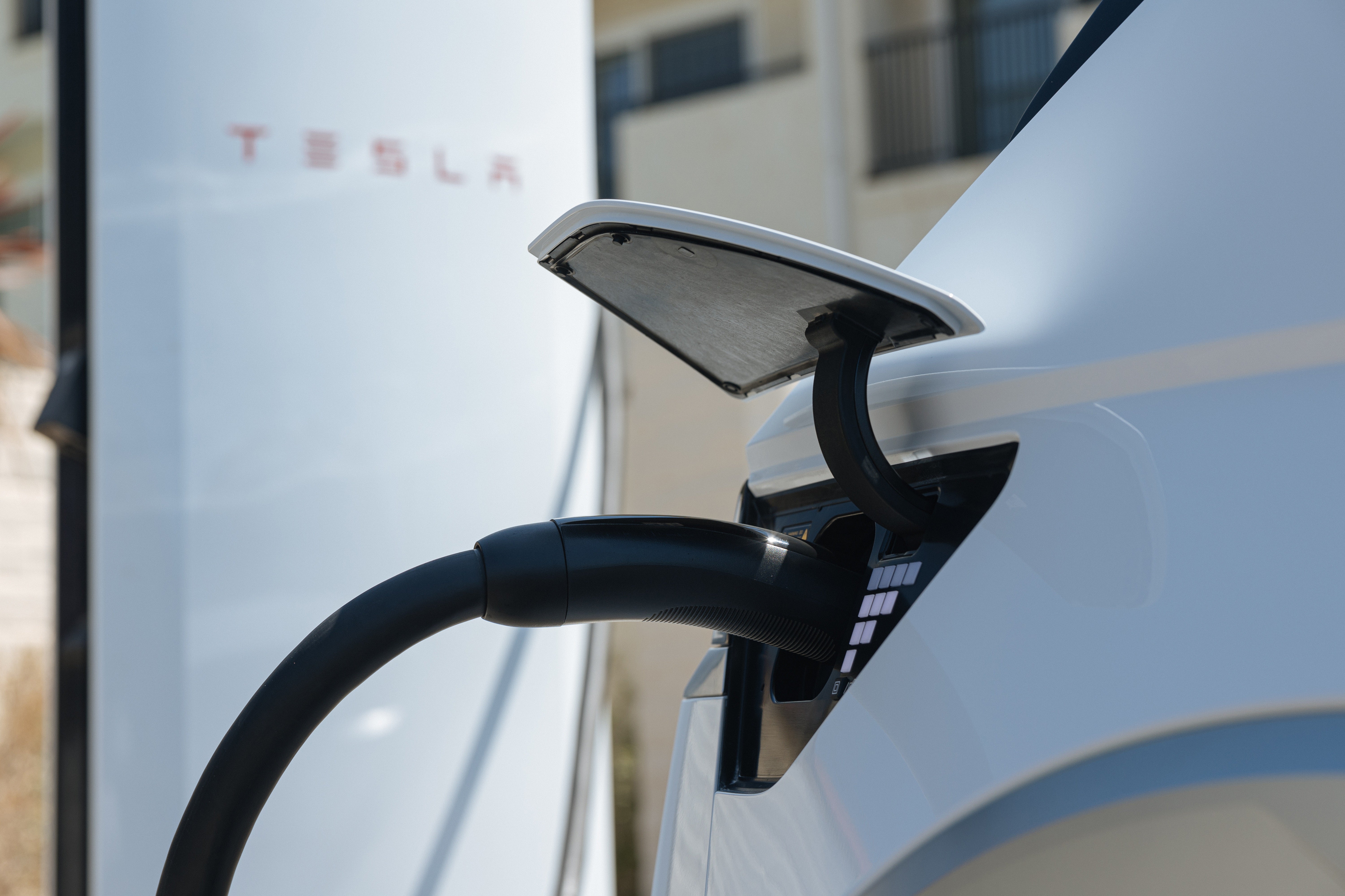 A charger is plugged into the charging port of a white 2026 Hyundai EV in Avondale, seen up close.